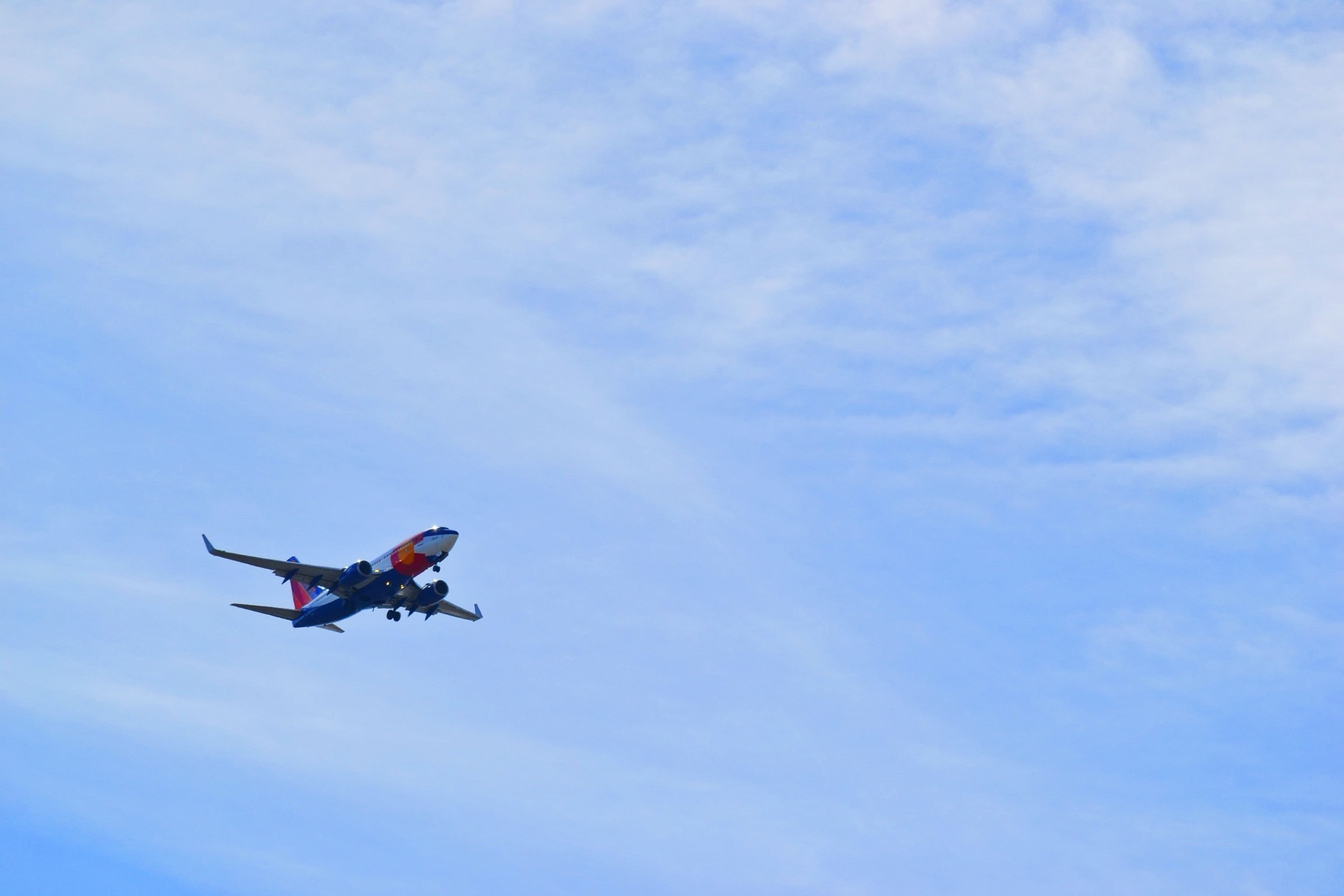 Commercial airplane climbing into a blue sky