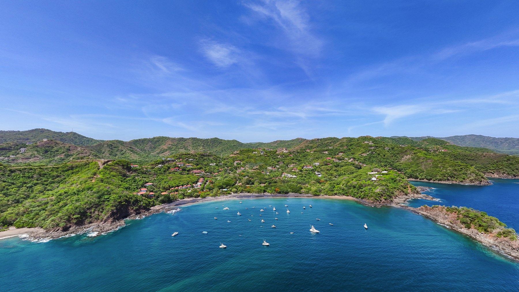 Aerial view of red-roofed neighborhoods along Playas del Coco's bay, a common stop on property tours