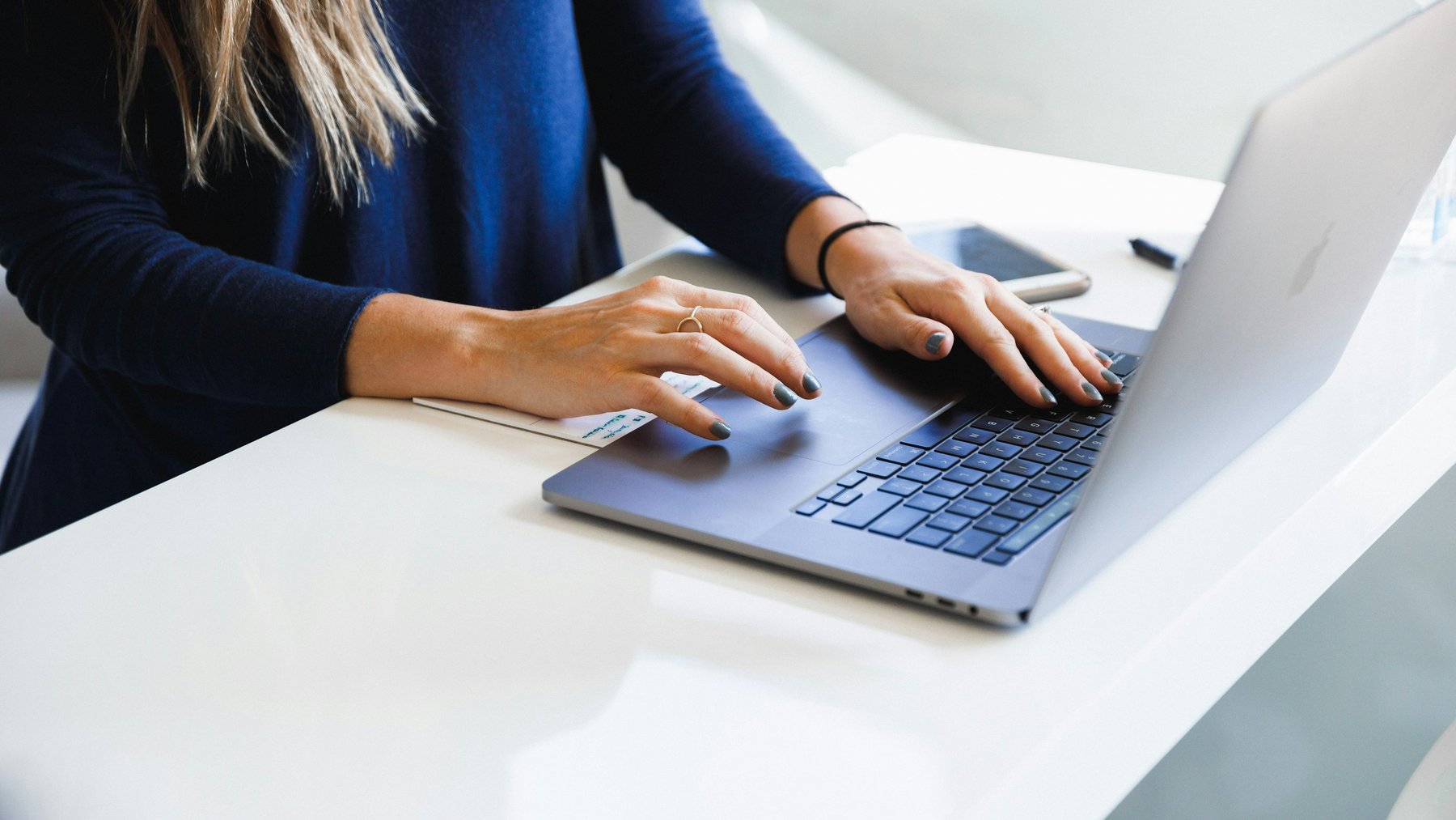 A person's hands typing on a laptop keyboard