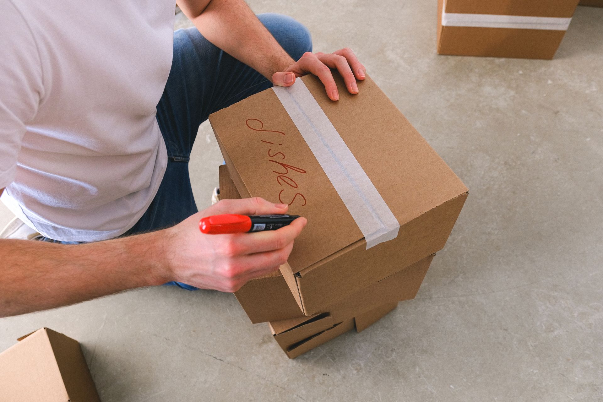 A person labeling a cardboard moving box with a marker
